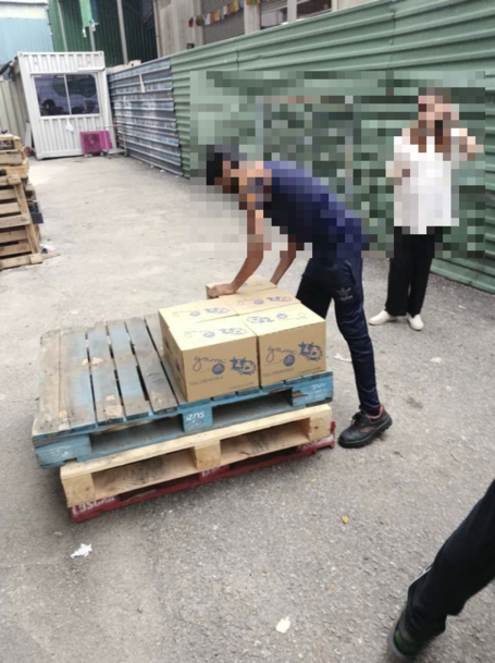 Farm Fresh milk cartons stacked on wooden pallets at a loading bay, with staff receiving the delivery.