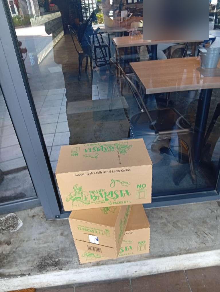 Master Barista milk boxes stacked outside a cafe's glass storefront.